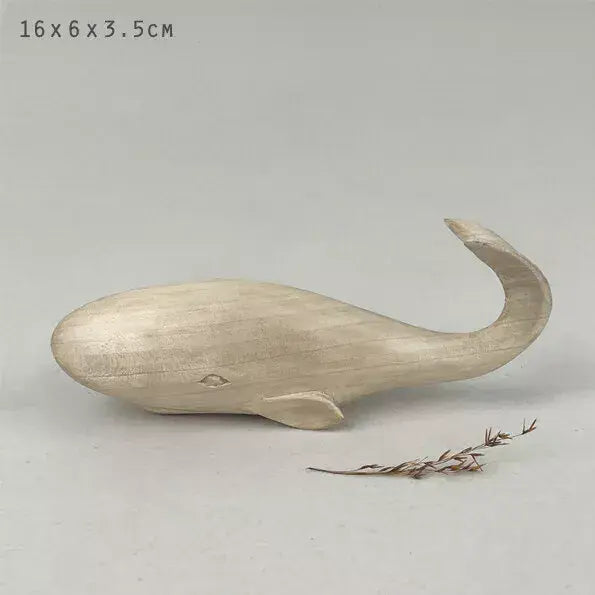 Small light coloured  wooden whale figurine on a light gray background